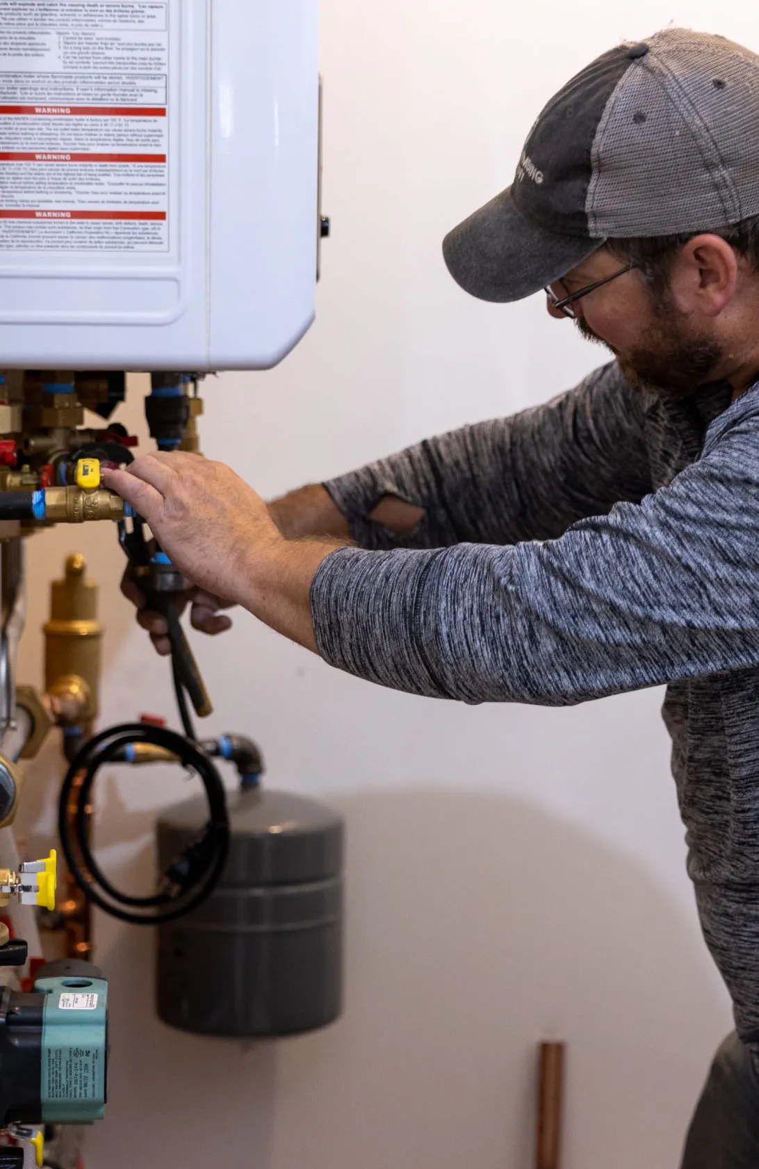 A man working on plumbing for a hot water heater.