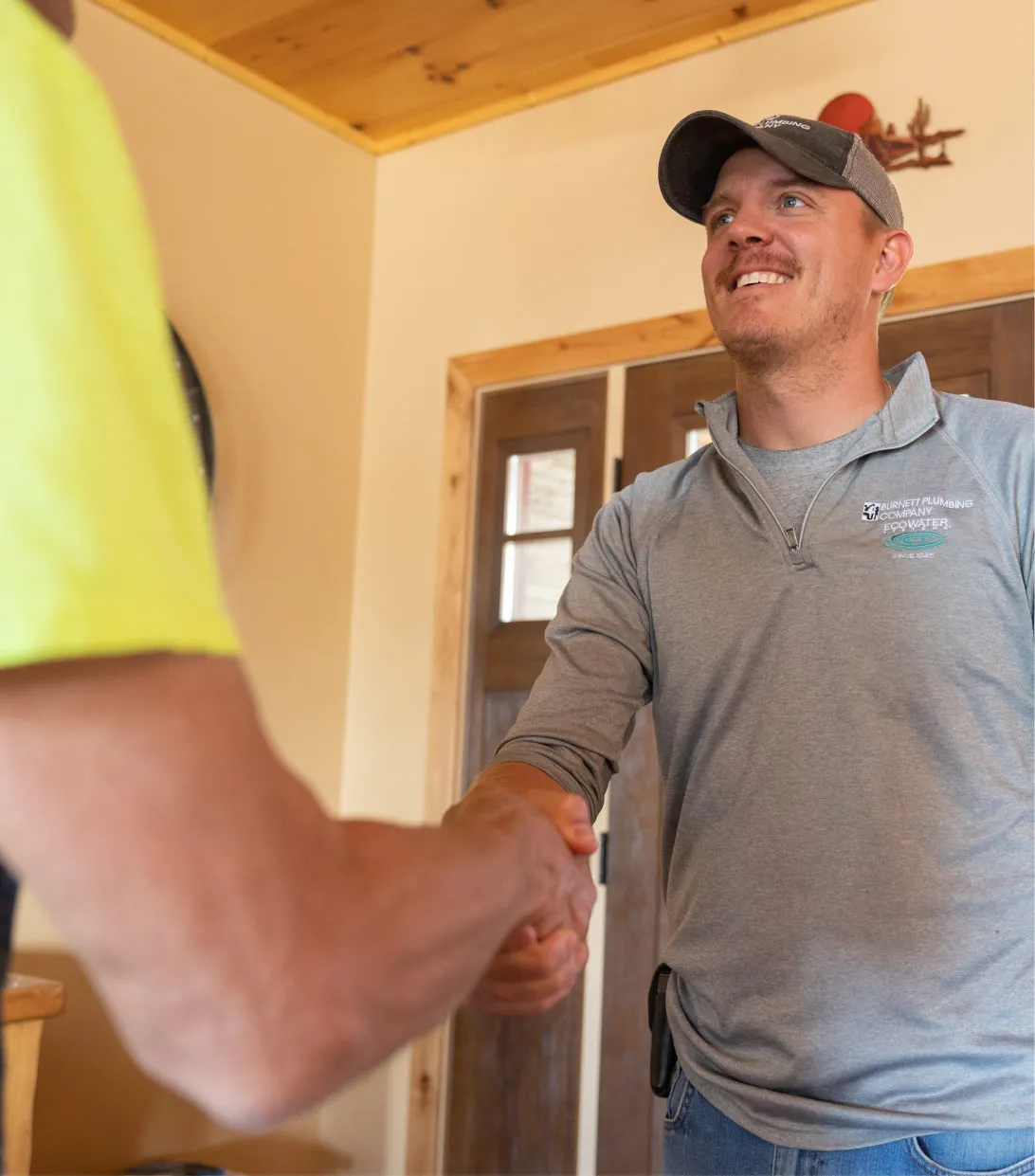 A smiling Luke Thoreson, owner of Burnett Plumbing Company shaking hands with a customer. 