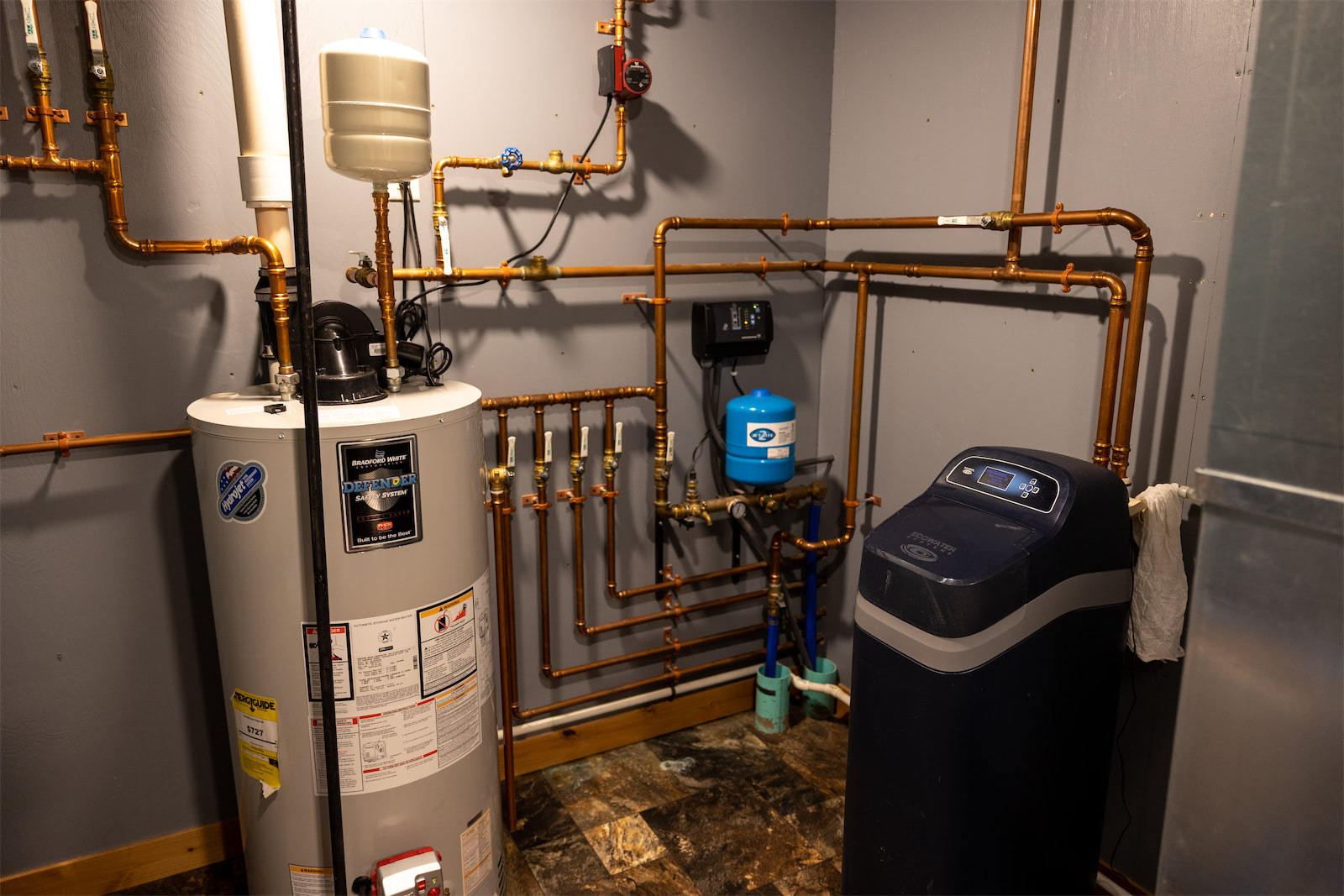 A utility room with an ecowater system filtration system and hot water heater.